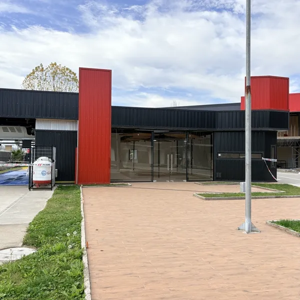 Acceso principal con columnas rojas y piso adoquín terminado