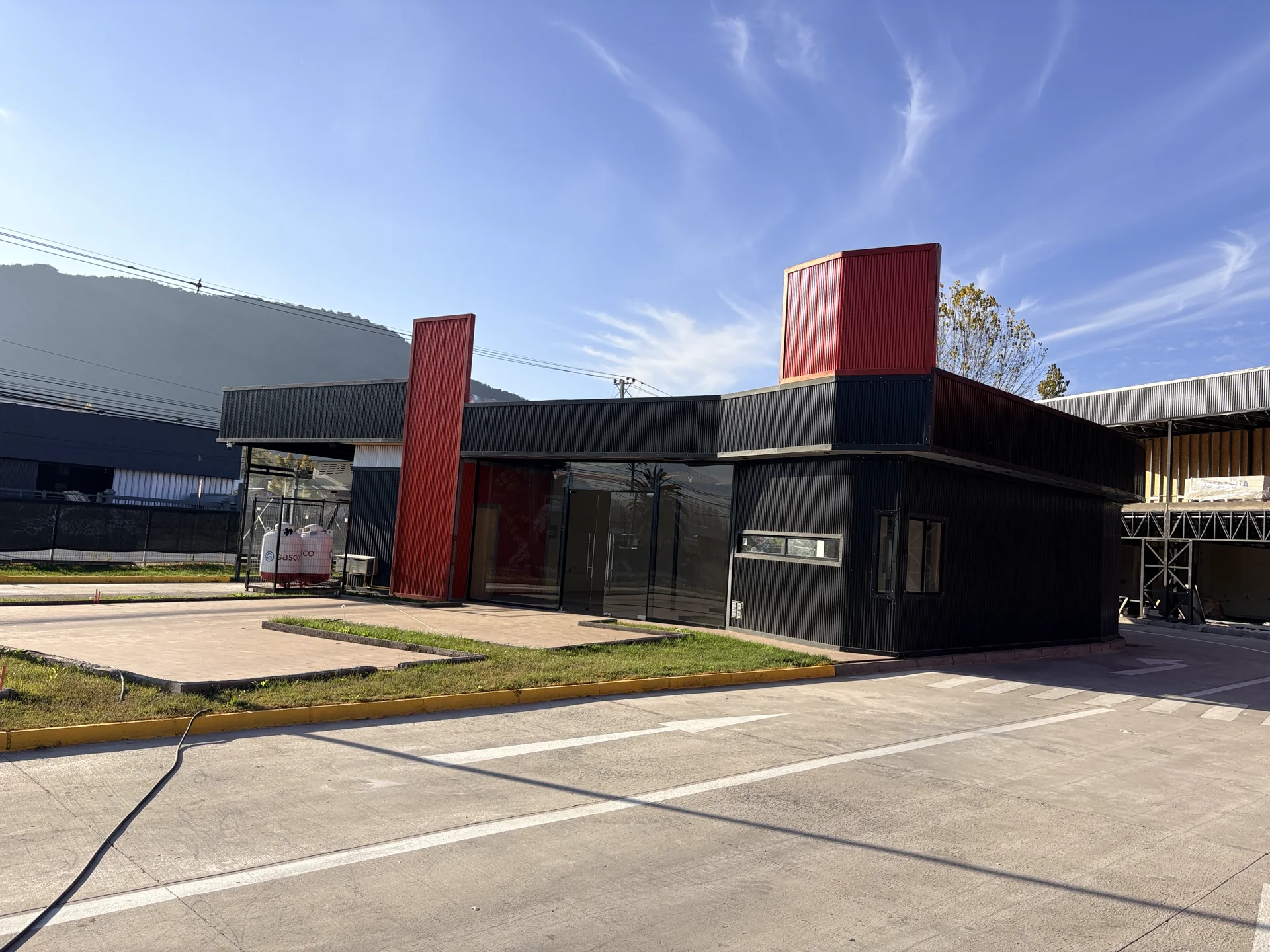 Acceso y fachada de Open Boulevard Coltauco con las columnas rojas y la cordillera al fondo