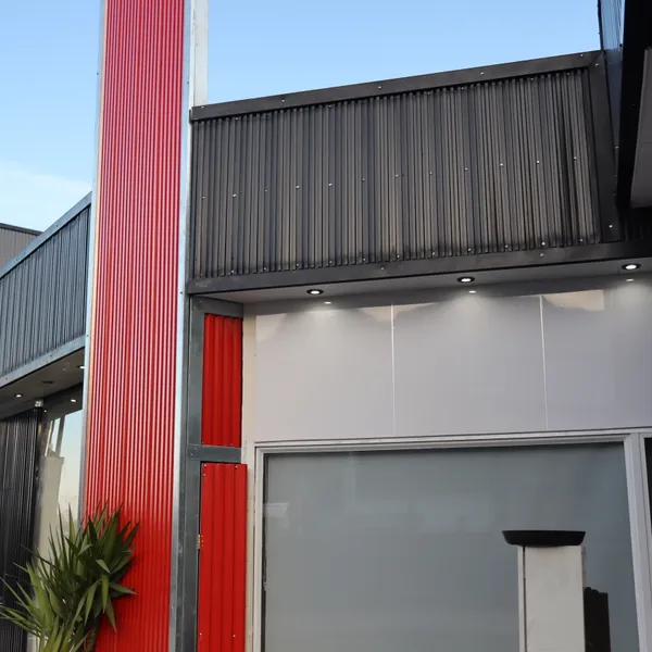 Detalle de fachada con columna roja y luces puntuales al atardecer