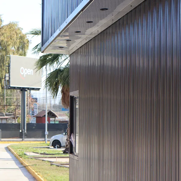 Señal OPEN sobre paneles corrugados negros y palmera