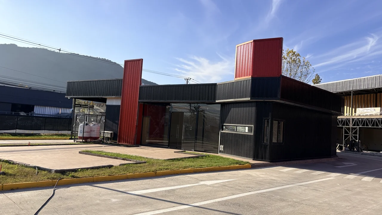 Vista aérea de Open Boulevard Coltauco — frente comercial con palmera, parking demarcado, locales con techo rojo y la Ruta H-30 al costado con la cordillera al fondo